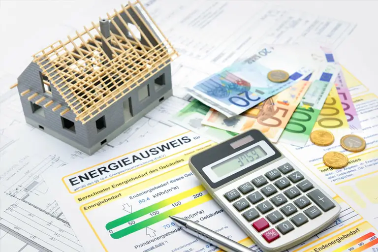 Ein Energieausweis, ein Rechner, Pläne und vieles mehr auf einem Schreibtisch – symbolische Darstellung für den Online Energieausweis der Wüstenrot Energieberatung