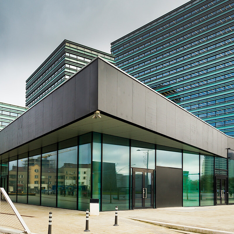 Ein moderner gewerblicher Häuserkomplex mit Glasfronten und mehreren (Hoch-)Häusern - symbolische Darstellung des förderfähigen energetischen Sanierungskonzeptes für Nichtwohngebäude gemäß DIN V 18599 durch die Wüstenrot Energieberatung