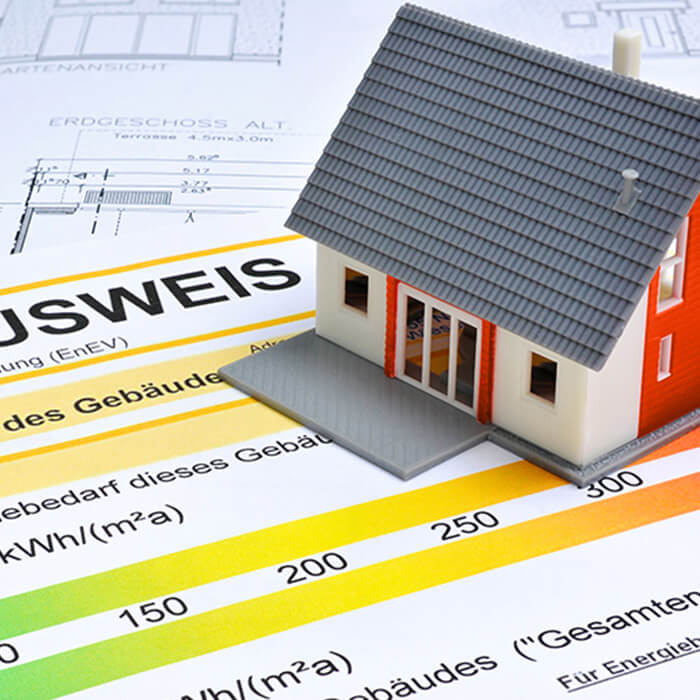 Ein Energieausweis, ein Grundriss und ein kleines Haus auf einem Schreibtisch – symbolische Darstellung für Online-Energieausweise der Wüstenrot Energieberatung