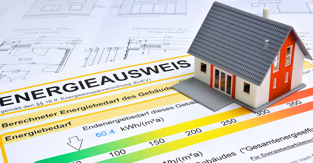 Ein Energieausweis, ein Grundriss und ein kleines Haus auf einem Schreibtisch – symbolische Darstellung für Online-Energieausweise der Wüstenrot Energieberatung